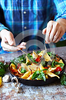 Chef mixes pasta with basil and spices in a pan. Appetizing pasta in a pan with tomatoes, basil and spices. One pan pasta. Italian