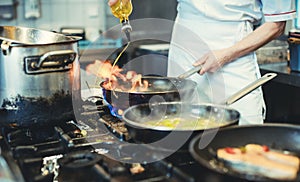 Chef with pans on the stove cooking in a restaurant kitchen
