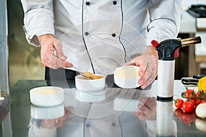 Chef or Patissier preparing a creme brulee photo