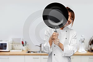 chef peeking out from behind frying pan on kitchen