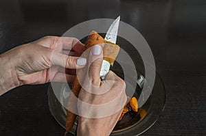 The chef peels boiled carrots with a knife