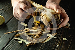 The chef peels raw sugar beet in a hotel kitchen before preparing a national dish. Close-up of a cook hands with a vegetable