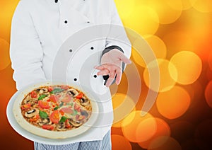 Chef with pizza against blurry orange bokeh