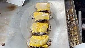 The chef places the cheese on top of the meat and burns the fire to allow the cheese to melt