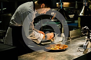 Chef plating dish on kitchen counter while recording at kitchen hotel