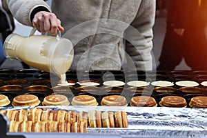 The chef is pouring the dough onto the stove with a hole for making pancakes.