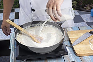 Chef pouring fresh milk the pan for cooking mushroom cream soup