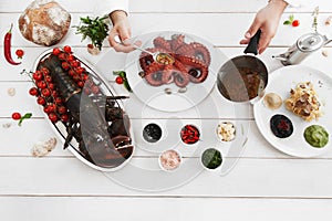 Chef pouring octopus with special sauce, flat lay