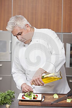 Chef Pouring Olive Oil Over Salad