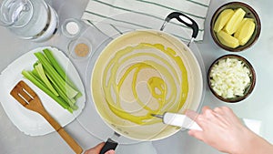 Chef pouring olive oil in a pot. Creamy pureed celery soup recipe