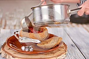 Chef pouring ukrainian borshch in bread pot.