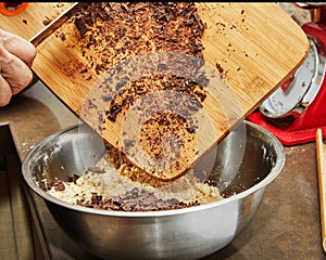 Chef pours chocolate into bowl of crumbs to make chocolate cake