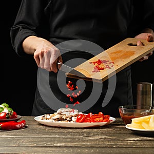 The chef pours hot chilli peppers into a plate. For cooking burritos, pizza, lettuce. A delicious and spicy food concept, Mexican