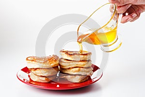 Chef pours sweet syrup on pancakes. White background