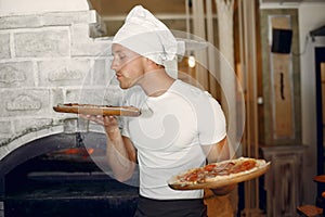 Chef in a white uniform prepare a pizzaa