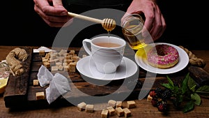 Chef prepares black tea with donuts. Close-up 4k video shooting, dark background