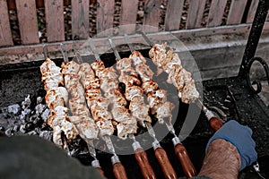 The chef prepares chicken shish kebab. Turkish Street food. Meat cooked over a fire, BBQ party in the backyard. Male hands in