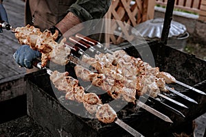 The chef prepares chicken shish kebab. Turkish Street food. Meat cooked over a fire, BBQ party in the backyard. Male hands in