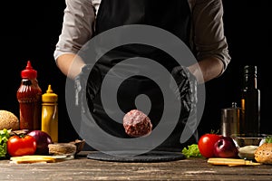 The chef prepares the cutlet with fresh ground beef, the ingredients on the background, cooking a delicious burger. Recipe book,