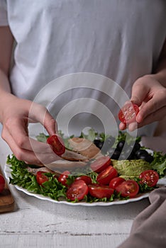The chef prepares a delicious diet meal of chicken breast, lettuce, avocado, tomatoes