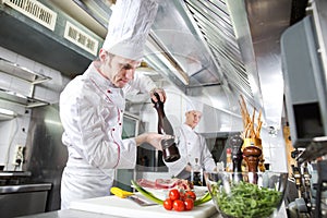 The chef prepares a dish in the kitchen of restoran.