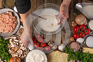 The chef prepares the dough. Lots of ingredients. Cooking pizza, pie, ravioli, pasta. Wooden texture. High angle view. Restaurant