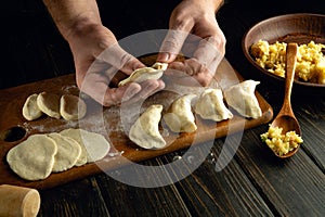 The chef prepares dumplings on the kitchen table with dough and potatoes. The concept of preparing a delicious breakfast with