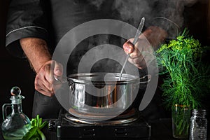 Chef prepares dumplings in a saucepan in the restaurant kitchen. Close-up of cook hands while cooking