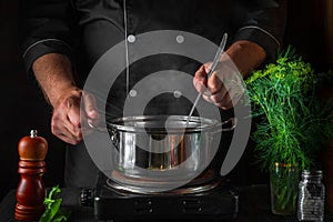 The chef prepares dumplings in a saucepan in the restaurant kitchen. Close-up of cook hands while cooking