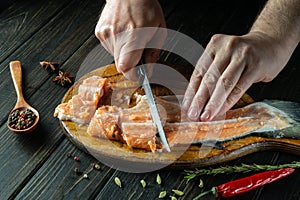 The chef prepares fresh Pink salmon fish. Preparing to cook fish food. The cook cuts with knife a red fish before roast