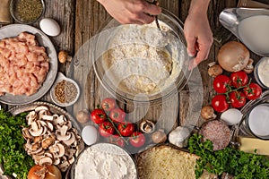 Chef prepares kneading dough, ingredients background.On old wooden table, cooking pizza or pie, top view flat lay