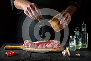 The chef prepares raw veal meat. Before baking, the chef adds a dry herbal seasoning to the beef. National dish is being prepared