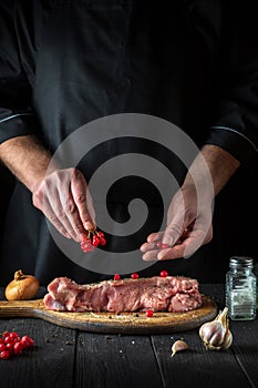 The chef prepares raw veal meat. Before baking, the cook puts the viburnum on the beef. National dish is being prepared in the