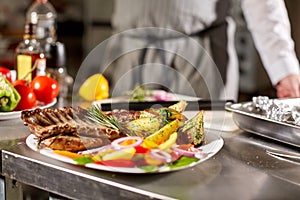 The chef prepares in the restaurant. Grilled rack of lamb with fried potatoes and fresh vegetables