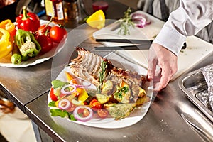 The chef prepares in the restaurant. Grilled rack of lamb with fried potatoes and fresh vegetables