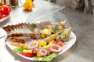 The chef prepares in the restaurant. Grilled rack of lamb with fried potatoes and fresh vegetables