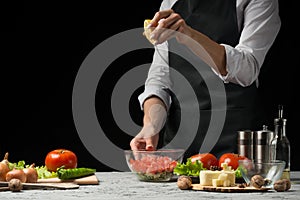 The chef prepares a salad, pours lemon juice on a dark background with an empty space for writing