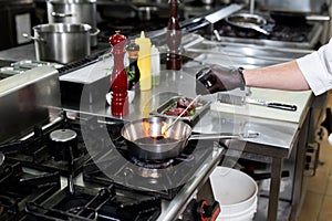 Chef prepares the sauce in a pan with red win.