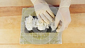 The chef prepares sushi by placing rice on the algae Nuri