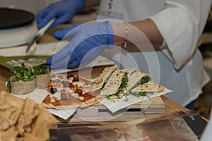 A Chef Preparing Appetizers based on Pieces of Pizza and Stuffed Italian Piadina