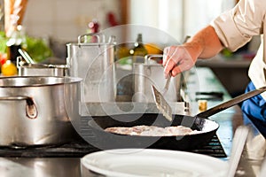 Chef preparing fish in restaurant or hotel kitchen