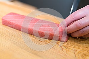 Chef preparing a fresh Tuna on a cutting board for otoro sushi