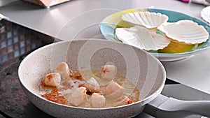 Chef preparing healthy gourmet food, seared scallops in a frying pan. A traditional dish of france and italy sea food