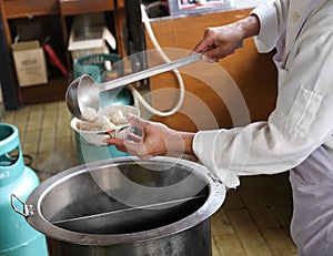 A chef is preparing meat ball noodle