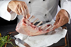 Chef preparing a rack of raw lamb chops