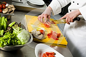 Chef preparing salad cutting tomato