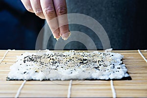 Chef preparing sushi roll over black table background