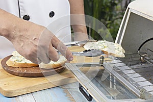 Chef put garlic bread to the oven by tongs