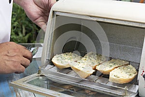Chef put garlic bread to the oven by tongs