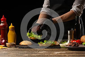 Šéfkuchař klade na hamburger bochník proti z složení. vynikající škodlivý jídlo rychle jídlo domácí 